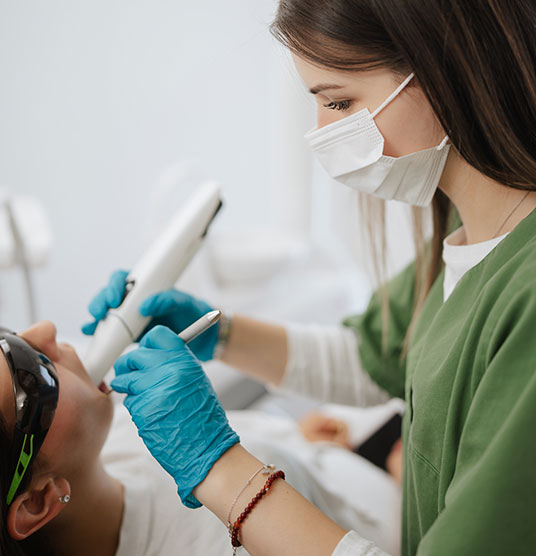 Eine dunkelhaarige Arzthelferin während der Behandlung an einem Patienten