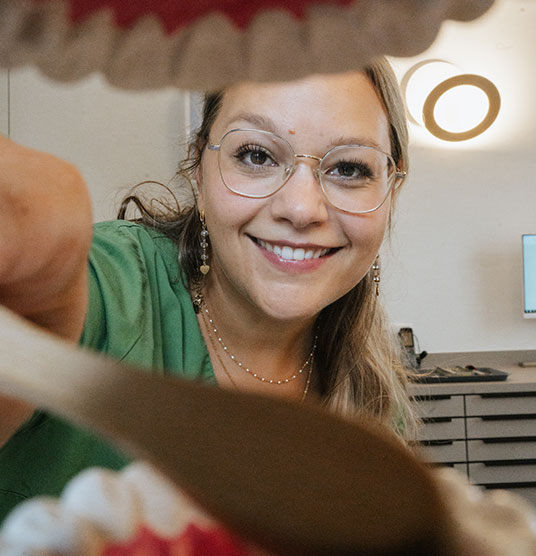 Aus einem Zahnmodel heraus fotografiert, wie eine Arzthelferin die Zahnbürste hinein hält