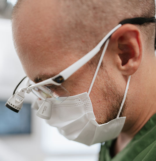 Eine Detailaufnahme von der Seite von Dr Neubert während er eine Zahnbehandlung durchführt