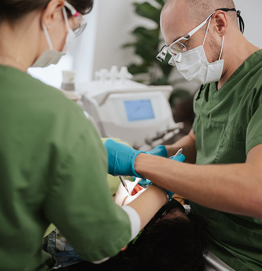 Dr Neubert führt an einem Patienten eine Zahnbehandlung durch