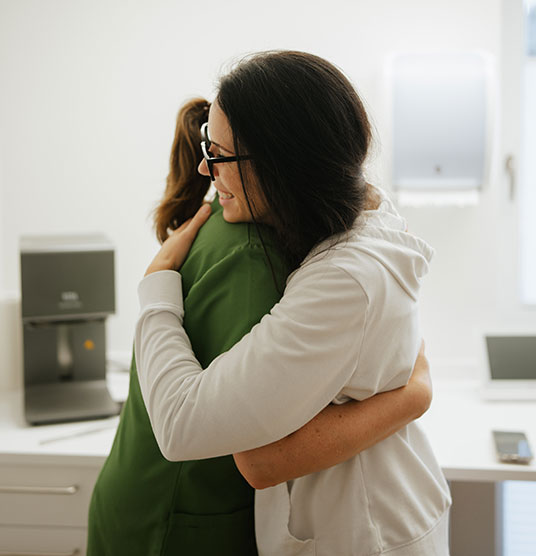Seitenansicht, wie sich zwei Damen in der Praxis umarmen